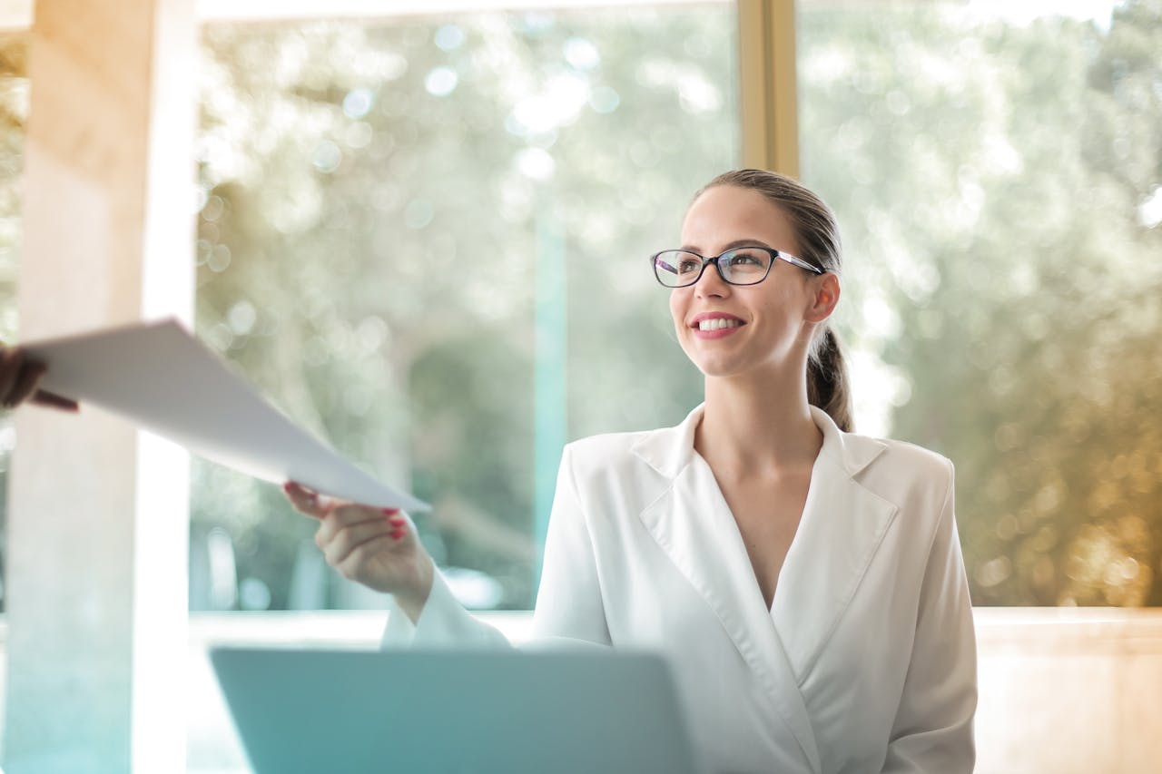 featured-portfolio-04 Low angle of successful female executive manager in classy style sitting at table with laptop in contemporary workplace and passing documents to colleague